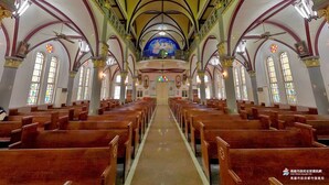 Interior d'una església amb files de bancs, sostres apuntats, vitralls i un altar central.