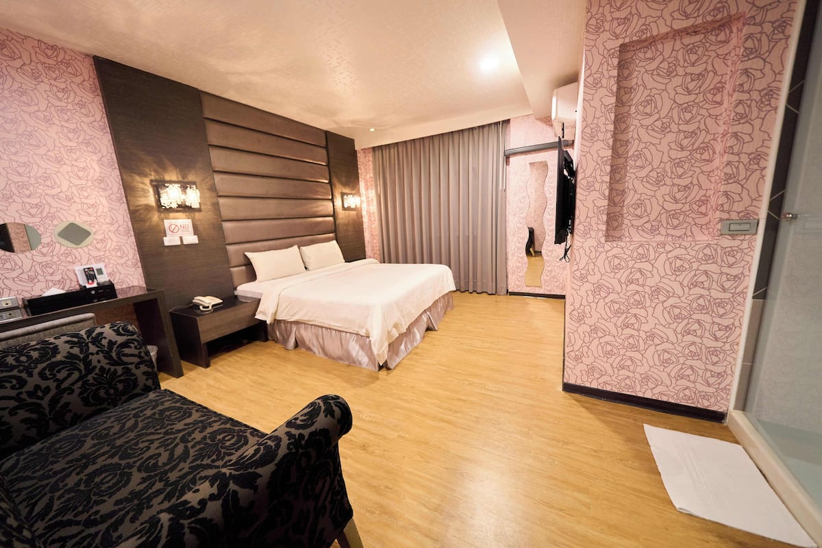 Une chambre d’hôtel avec un lit, une table de chevet, une lampe et un miroir.