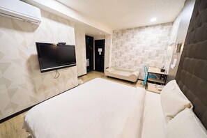 A hotel room with a large bed, a flat-screen TV mounted on the wall, a bedside table, and a bathroom with a mirror and sink. - The River Fashion Hotel (Kaohsiung)
