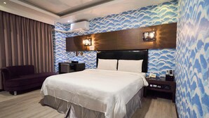 Habitació d'hotel amb un llit, una taula de nit, un telèfon, un sofà i una paret amb un disseny d'ona.