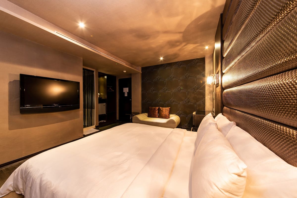Une chambre d’hôtel dotée d’un grand lit, d’un téléviseur à écran plat fixé au mur et d’une tête de lit à motifs.