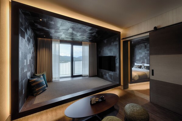 Una habitación de hotel moderna con un ventanal grande, un televisor de pantalla plana, un sofá, una mesa de centro y una cama.