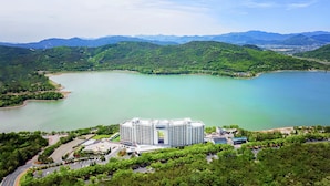 A hotel with a modern design, surrounded by lush greenery and a large lake. - Sono Calm Gyeongju (Gyeongju)