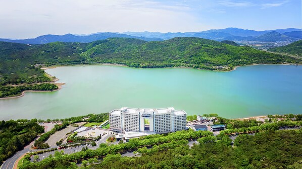 A hotel with a modern design, surrounded by lush greenery and a large lake. - Sono Calm Gyeongju (Gyeongju)