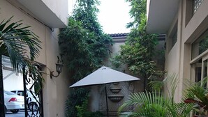 Un patio con suelo de baldosas, una mesa con sillas y plantas en macetas.