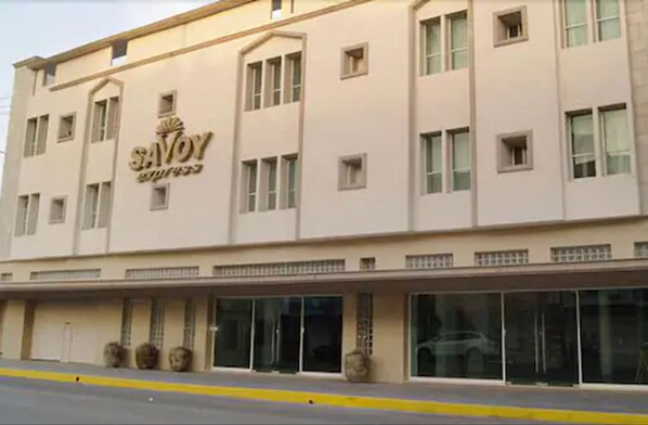 Un bâtiment sur lequel on peut lire l’inscription « SAVOY HOTEL » et qui possède de nombreuses fenêtres.