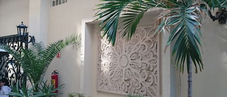 Une cour avec des plantes en pot, un mur décoratif et un extincteur.