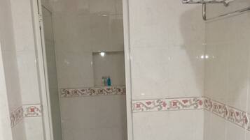 A bathroom with a toilet, a shower stall, and a towel rack.