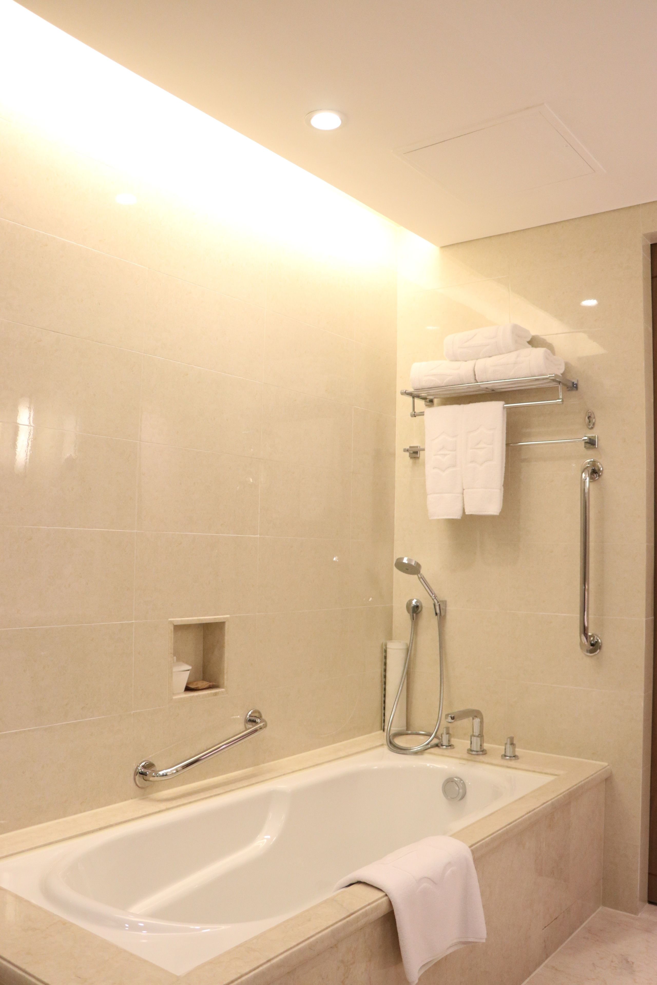 A modern bathroom with a bathtub, a shower, and a handrail.