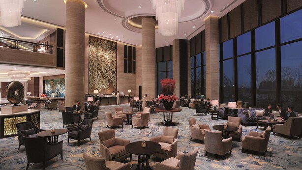 A spacious lobby with high ceilings, chandeliers, and a large seating area with multiple tables and chairs. - Shangri-La Yangzhou (Yangzhou)