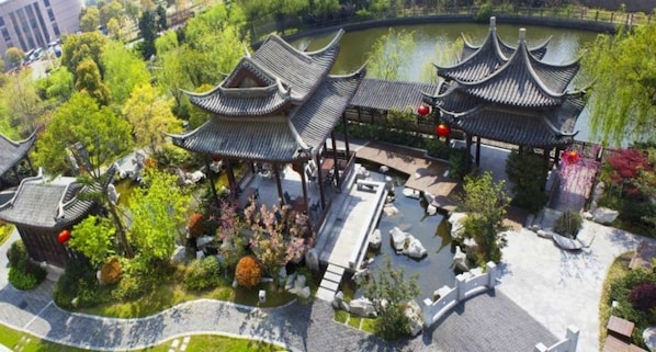 A traditional Chinese pavilion with multiple tiers, surrounded by lush greenery and a pond. - Shangri-La Yangzhou (Yangzhou)