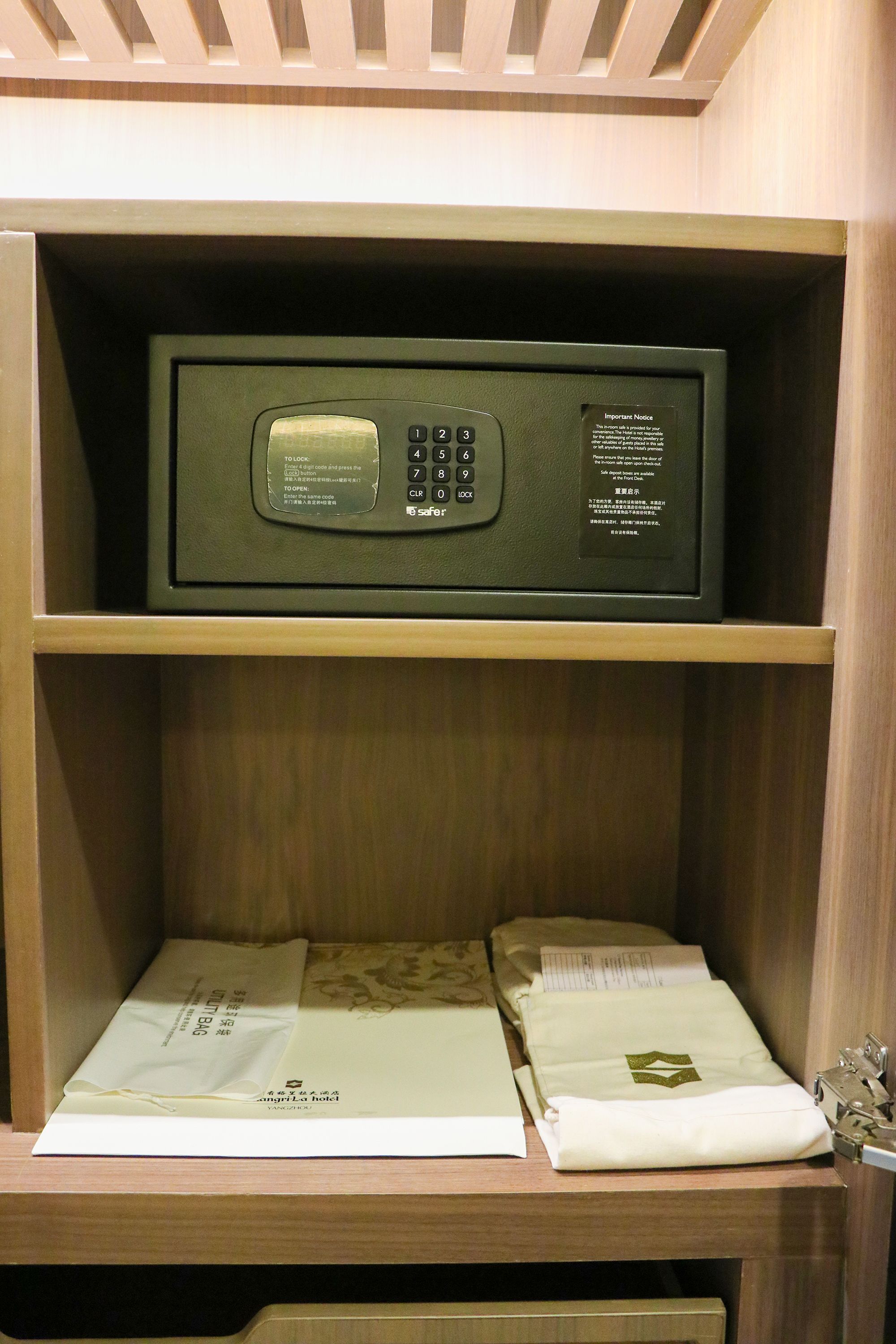 Een kluis met een keypad en een briefje aan de zijkant. Daaronder liggen twee opgevouwen items op een houten plank.