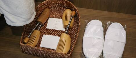 A wicker basket containing wooden utensils and a napkin, alongside a pair of white slippers.