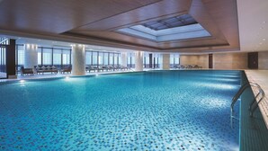 A large indoor swimming pool with tiled flooring, sunlit ceiling, and lounge chairs along the poolside. - Shangri-La Yangzhou (Yangzhou)