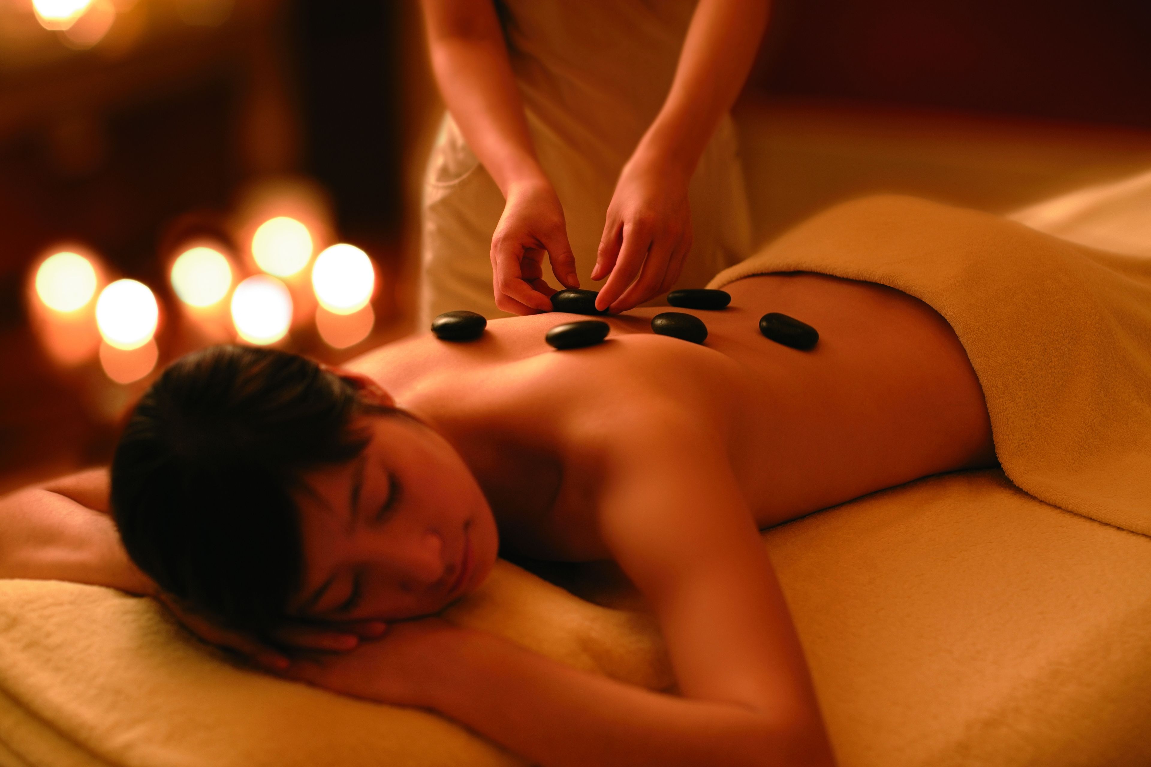 A person receiving a massage with stones on their back.