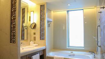 Un baño moderno con un espejo grande, una bañera y un ventanal que proporciona luz natural.