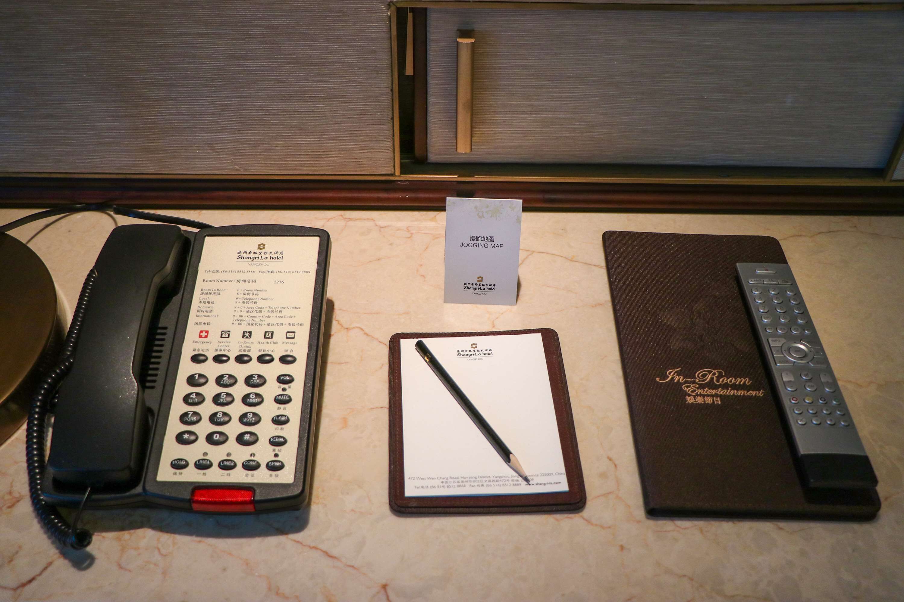 Ein Hotelzimmer mit Telefon, Stadtplan, Fernbedienung und Speisekarte.
