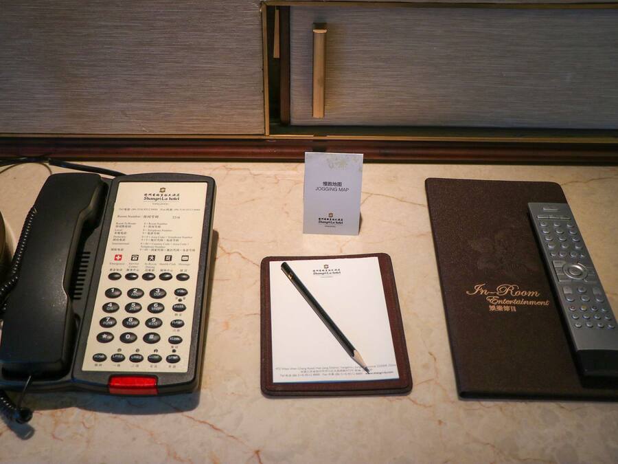 Ein Hotelzimmer mit Telefon, Stadtplan, Fernbedienung und Speisekarte.