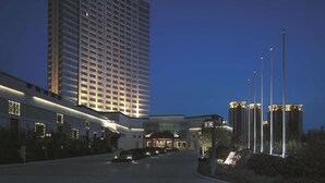 A modern hotel with a tall building, a well-lit entrance, and a landscaped area with street lamps. - Shangri-La Yangzhou (Yangzhou)