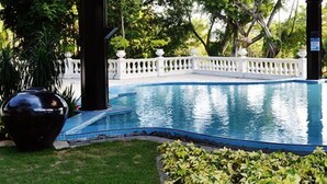 Piscina com cerca branca e placa com as regras para a piscina infantil.
