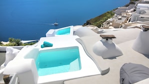 A seaside hotel with white architecture, a pool, and a view of the sea. - Onar Villas Oia - Onar Hotels Collection (Santorini)