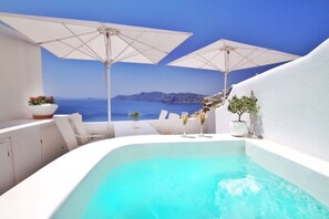 A white infinity pool with two white umbrellas, a white table with chairs, and a view of the sea. - Onar Villas Oia - Onar Hotels Collection (Santorini)