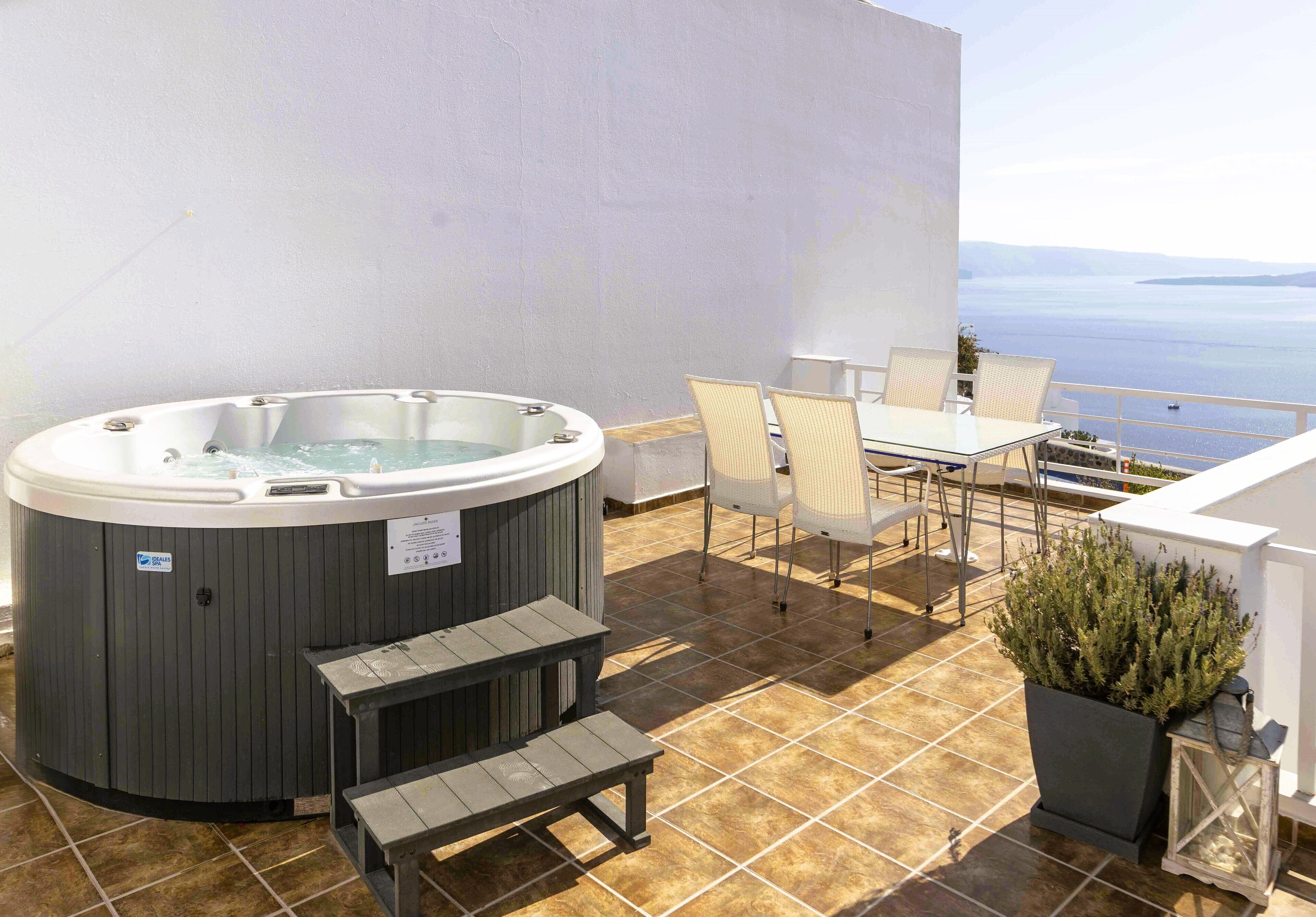 A hot tub, outdoor seating, and a view of the sea.