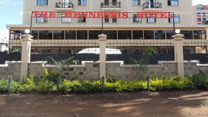 Un hotel con un letrero que dice "THE HENNESSIS HOTEL". Tiene varios balcones y un tejado de tejas.