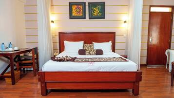 Une chambre d’hôtel avec un lit en bois, un bureau avec une chaise et deux œuvres d’art encadrées accrochées au mur.