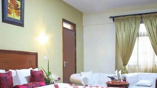 Una habitación de hotel con una cama, un sofá, una mesita y una puerta.