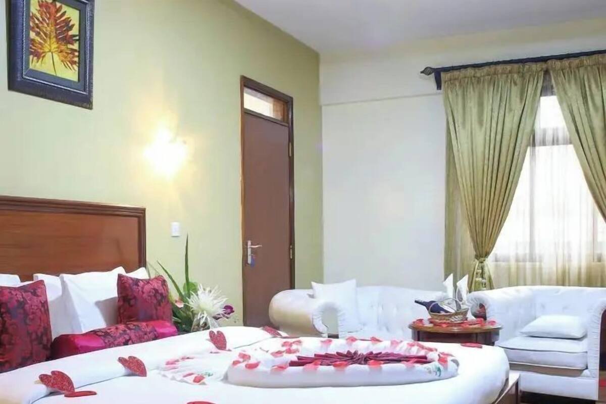 A hotel room with a bed, a sofa, a small table, and a door.