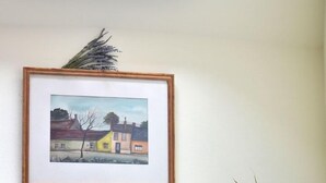 A framed painting of a rural scene on a wall, a potted plant in the foreground, and a brick wall. - Revesz Hotel (Gyor)