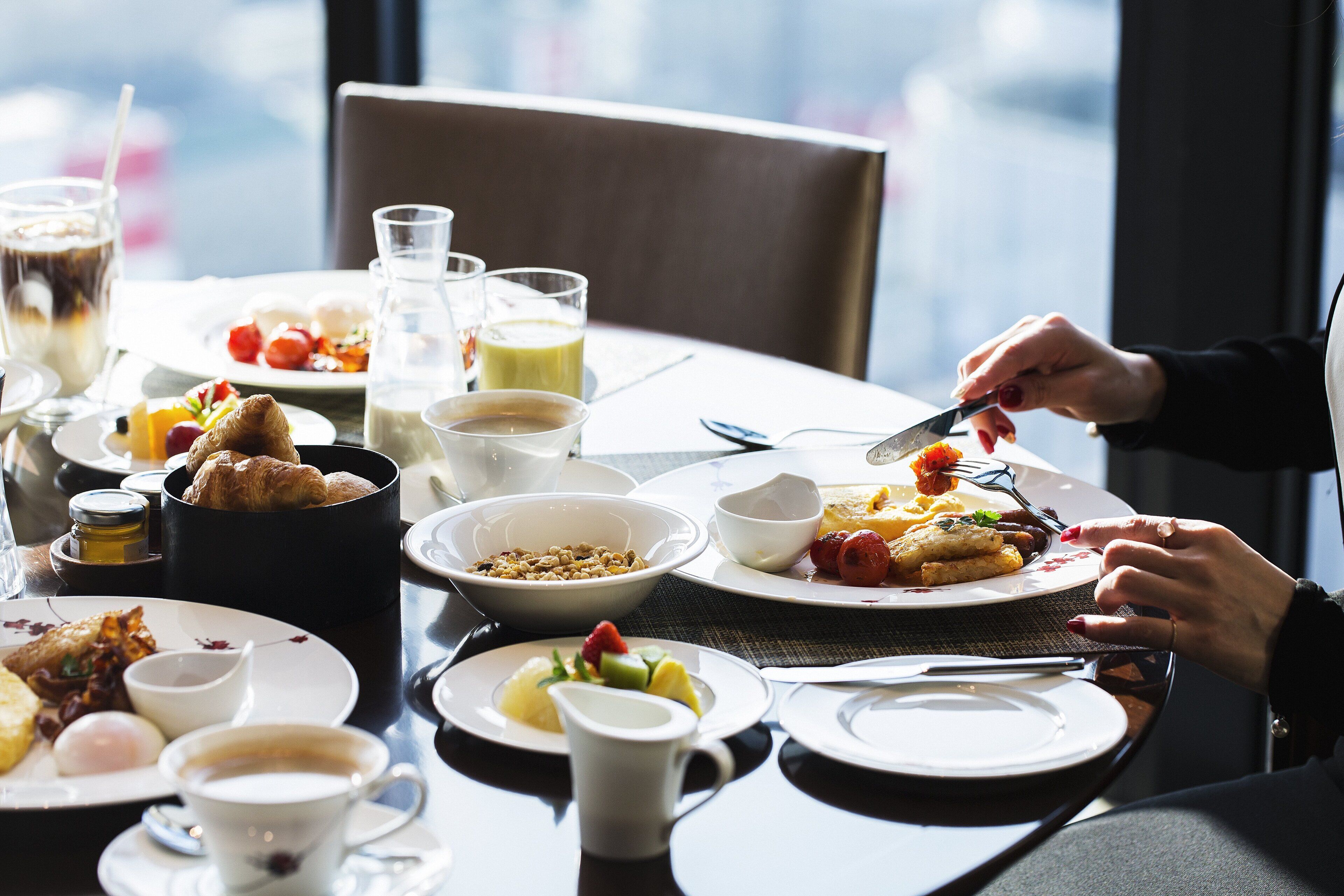 A breakfast setting with various dishes, including croissants, fruits, and beverages.