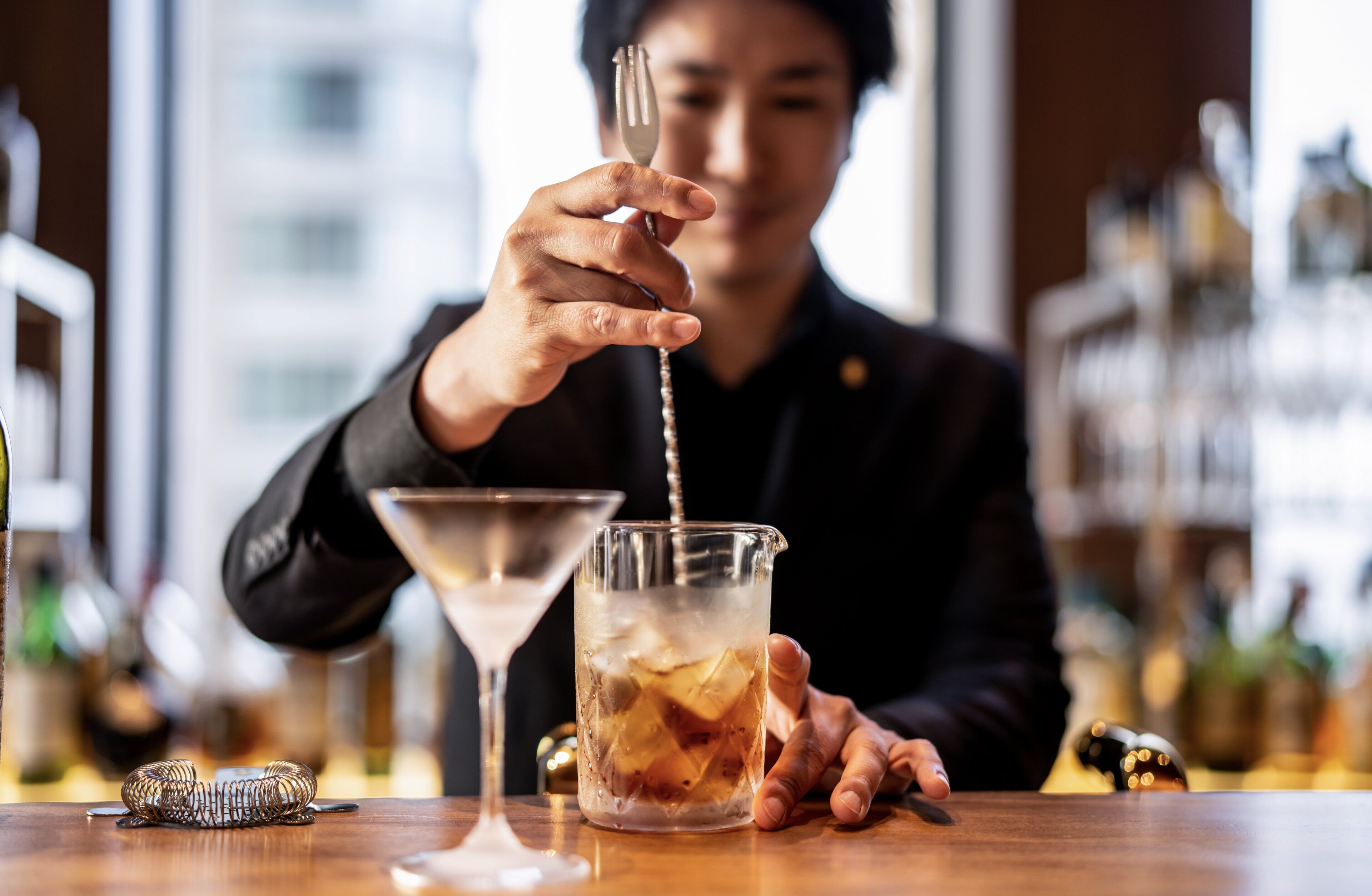 A bartender pouring a drink into a glass.