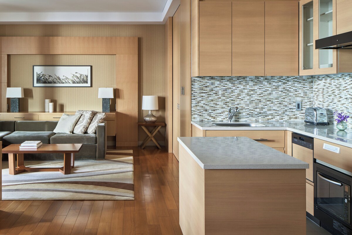 A modern kitchen with wooden cabinets, a tiled backsplash, and a built-in oven.