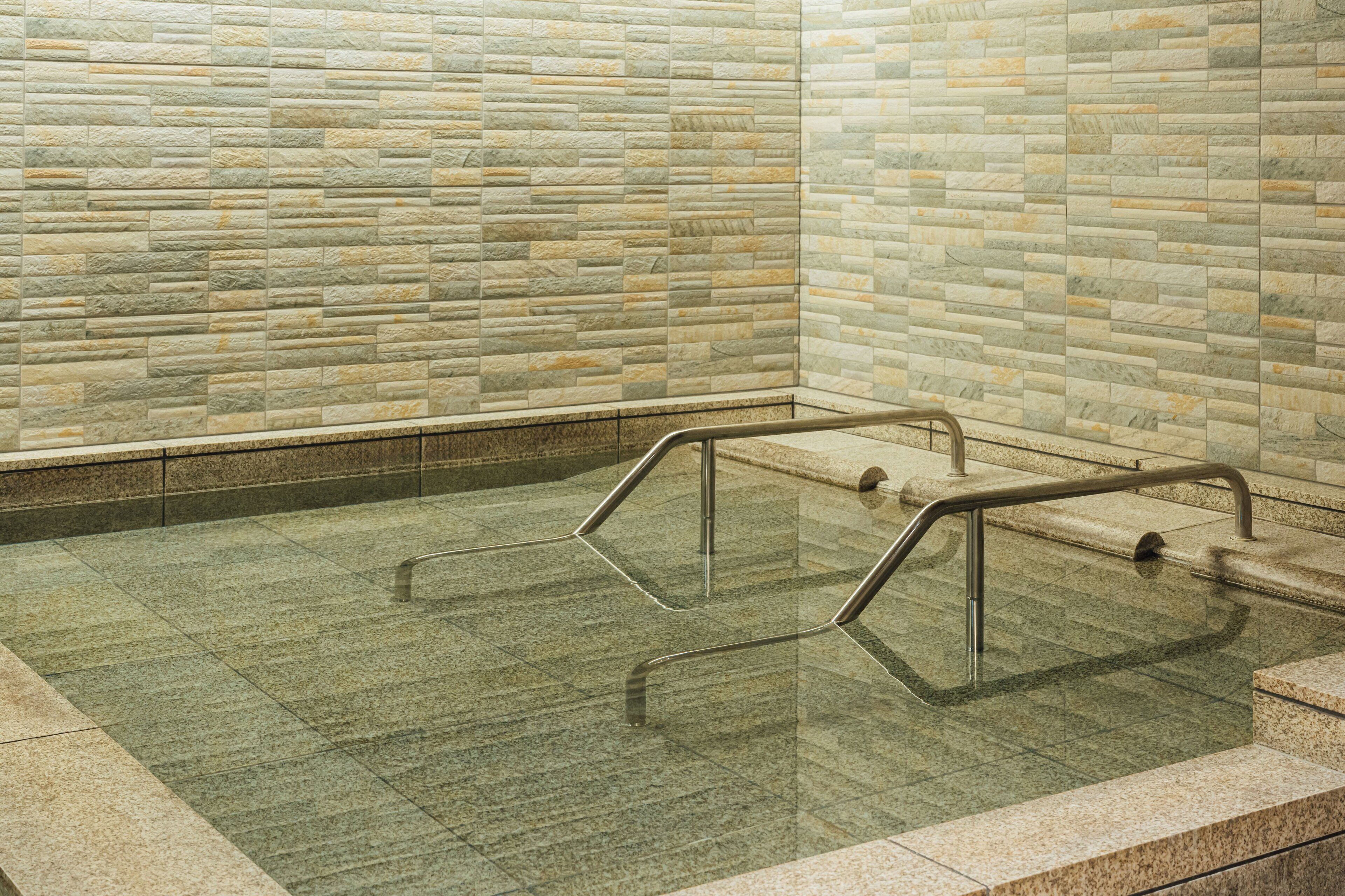 A stone-walled indoor pool area with metal handrails.