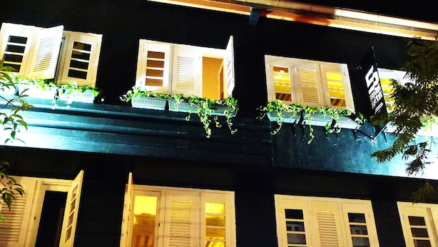 Un edificio con varias ventanas, algunas con contraventanas, y un letrero con caracteres chinos.
