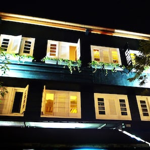 Un edificio con varias ventanas, algunas con contraventanas, y un letrero con caracteres chinos.