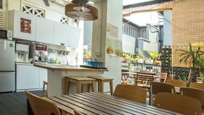 Un restaurante con mesa y sillas de madera, una zona de cocina y vistas al exterior.