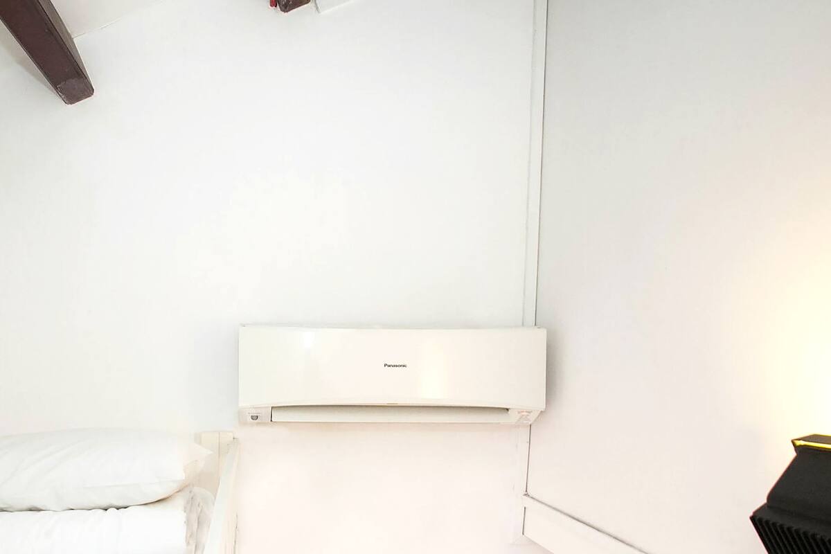Une pièce blanche avec un lit, un mur blanc et un plafond blanc.