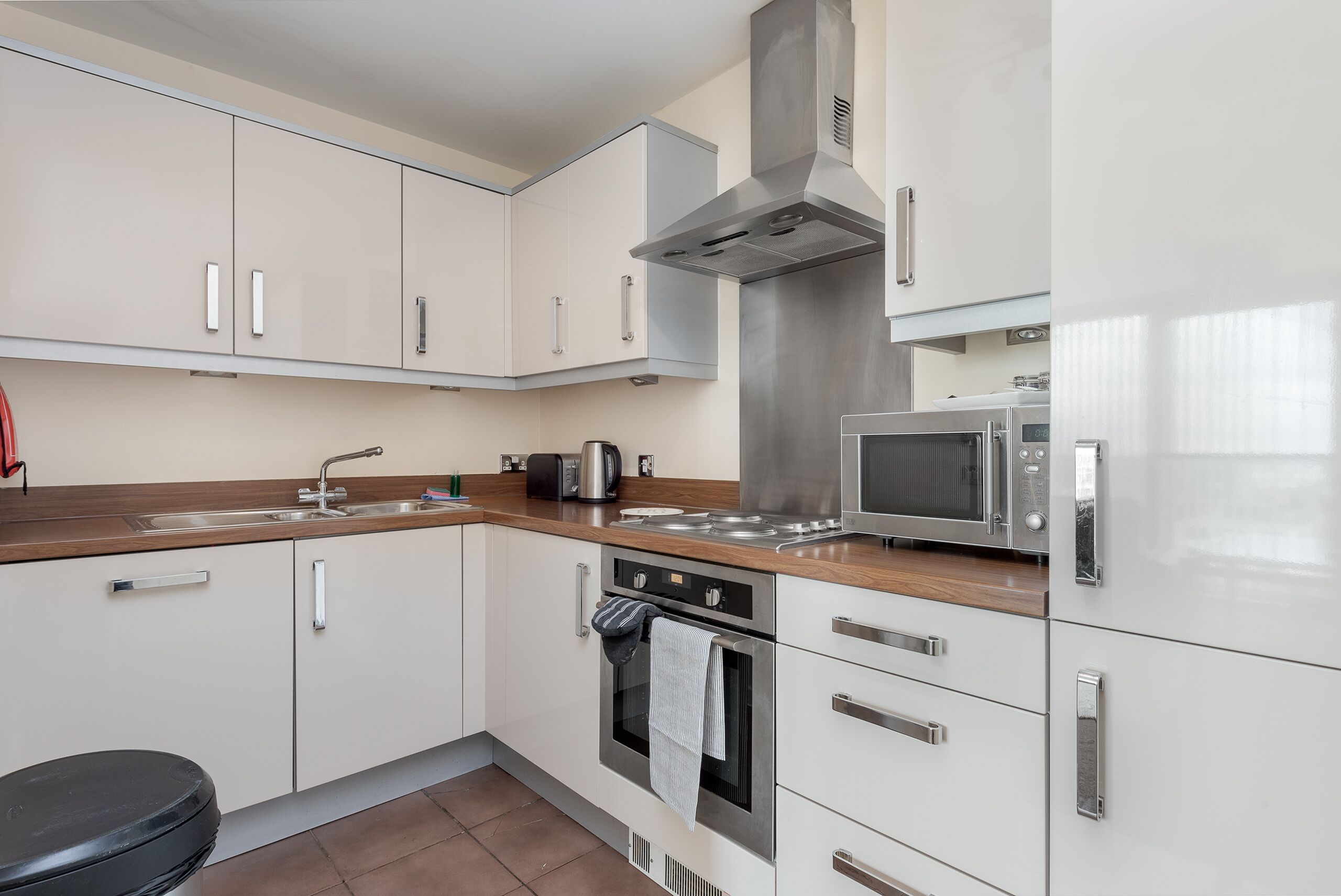 Una cocina moderna con armarios blancos, electrodomésticos de acero inoxidable y encimera de madera.