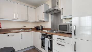 Una cocina moderna con armarios blancos, electrodomésticos de acero inoxidable y encimera de madera.