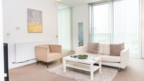 Ein modernes Wohnzimmer mit einem weißen Sofa, einem beigen Sessel und einem Glastisch.