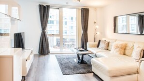 Ein modernes Wohnzimmer mit einer Couch, einem Couchtisch und einem Fernseher.