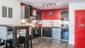 Eine moderne Küche mit roter Akzentwand, einer Kaffeemaschine und einem roten Kühlschrank.