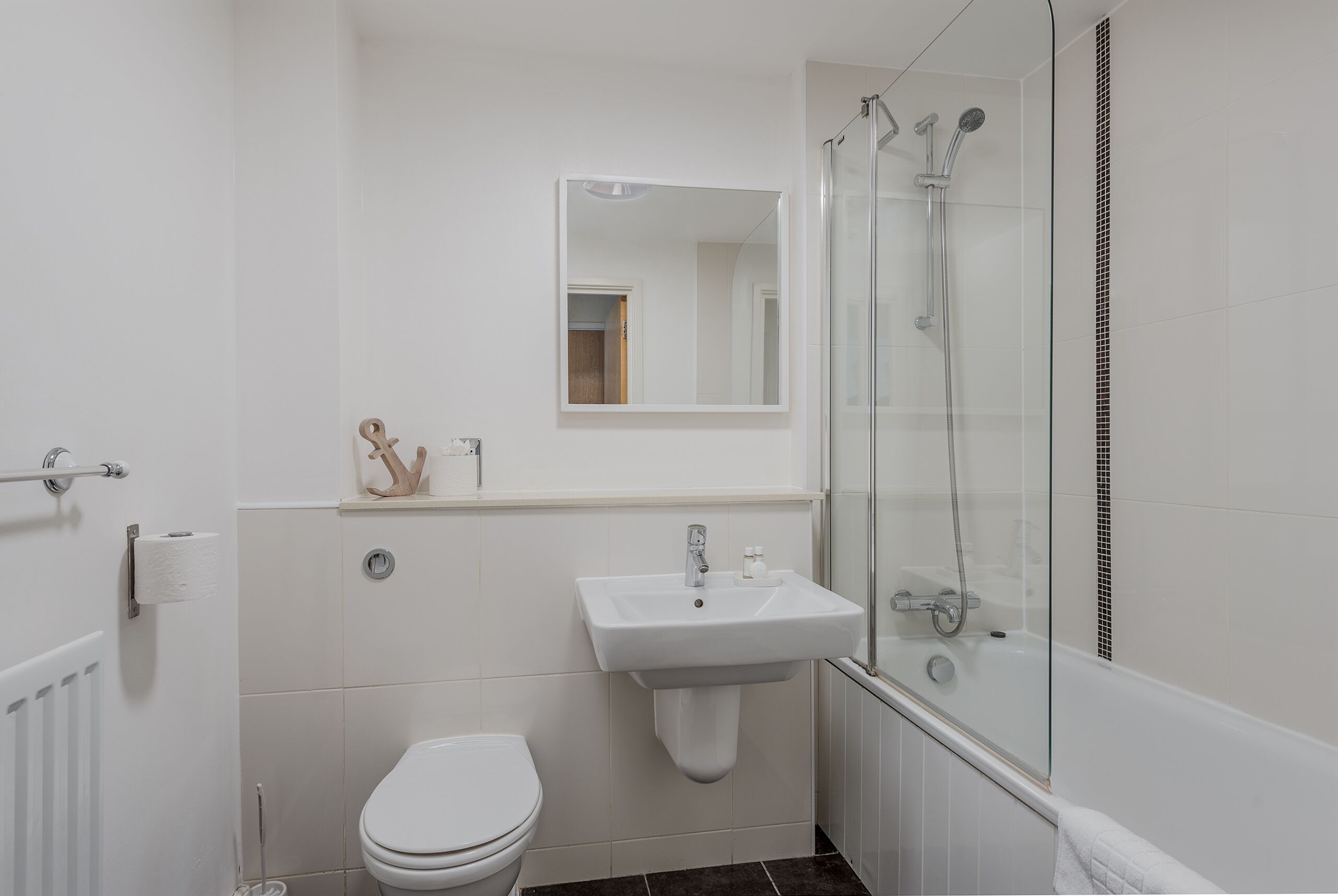 A small, modern bathroom with a toilet, sink, and glass-enclosed shower.