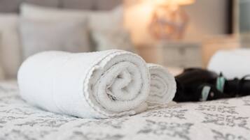 A neatly folded white towel on a bed with a patterned bedspread.