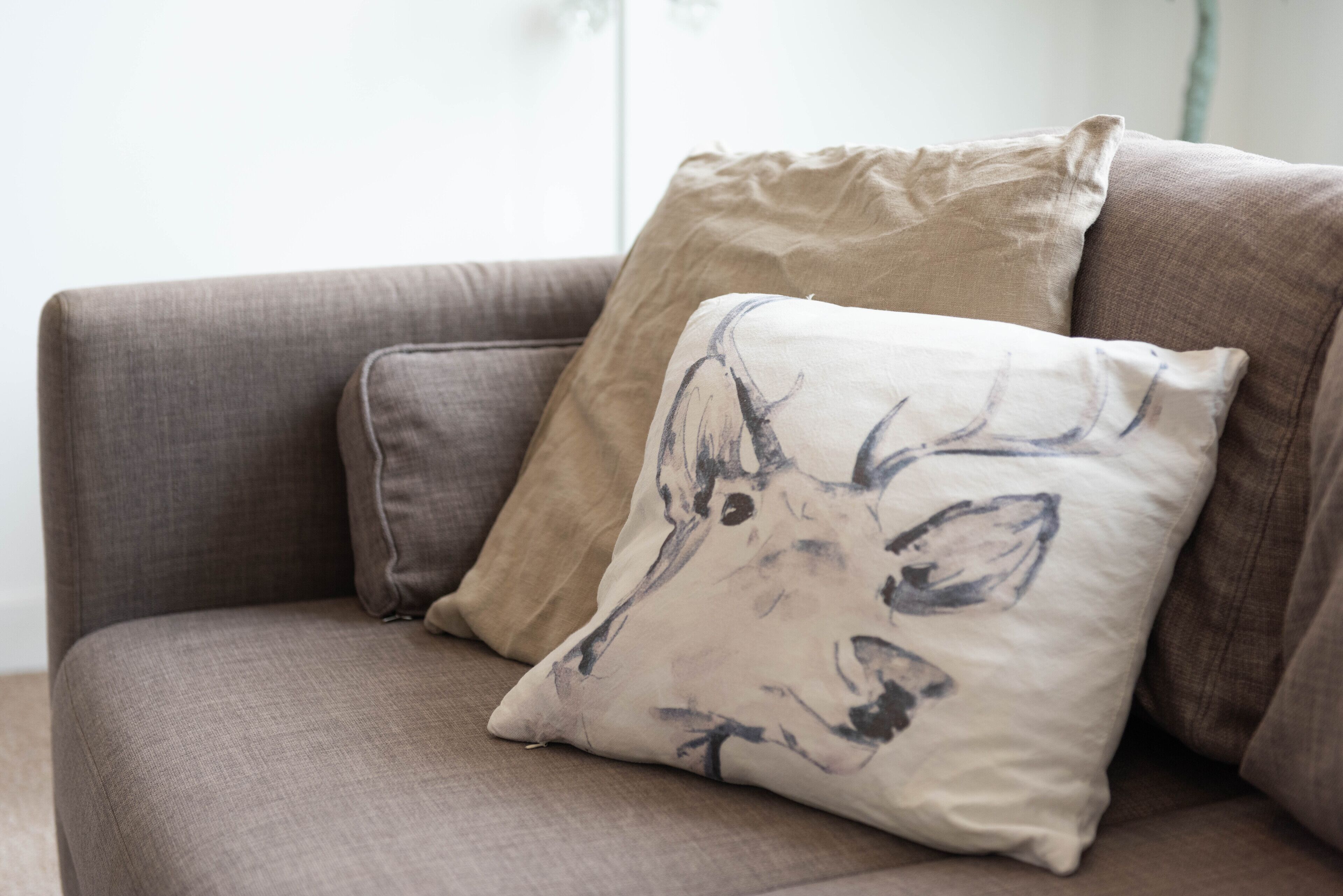 A sofa with two pillows, one plain and one with a deer design.