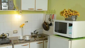 A kitchen with white cabinets, a microwave, a kettle, and a sink. - Susana Just B&B (Florida)