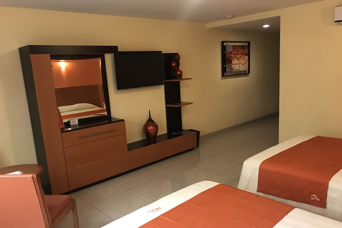 Ein Hotelzimmer mit zwei Betten, einem Fernseher, einer Minibar und einer Sitzecke.